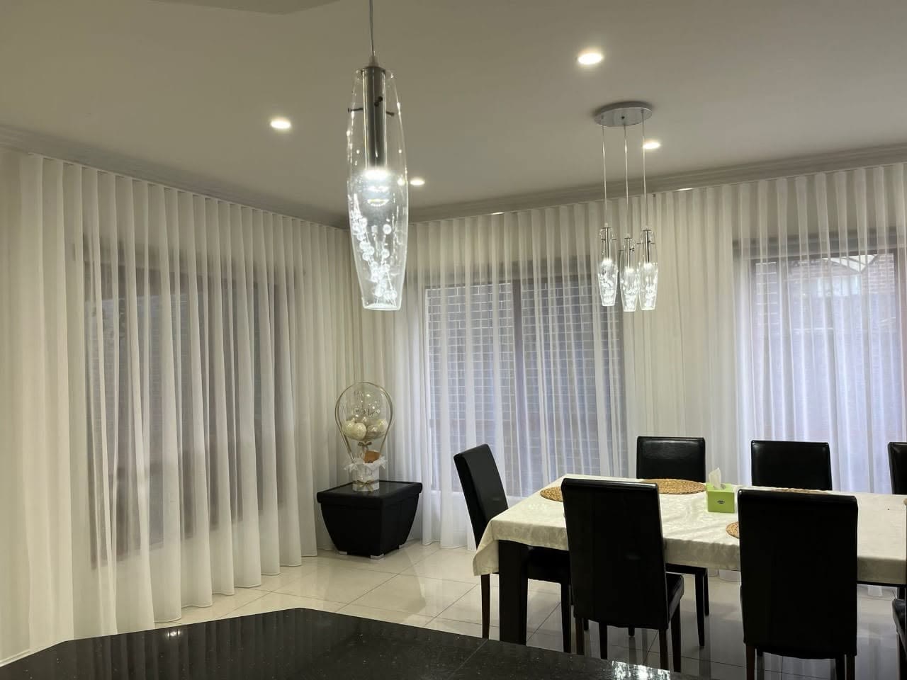 White sheer curtains in a pendant-lit dining room